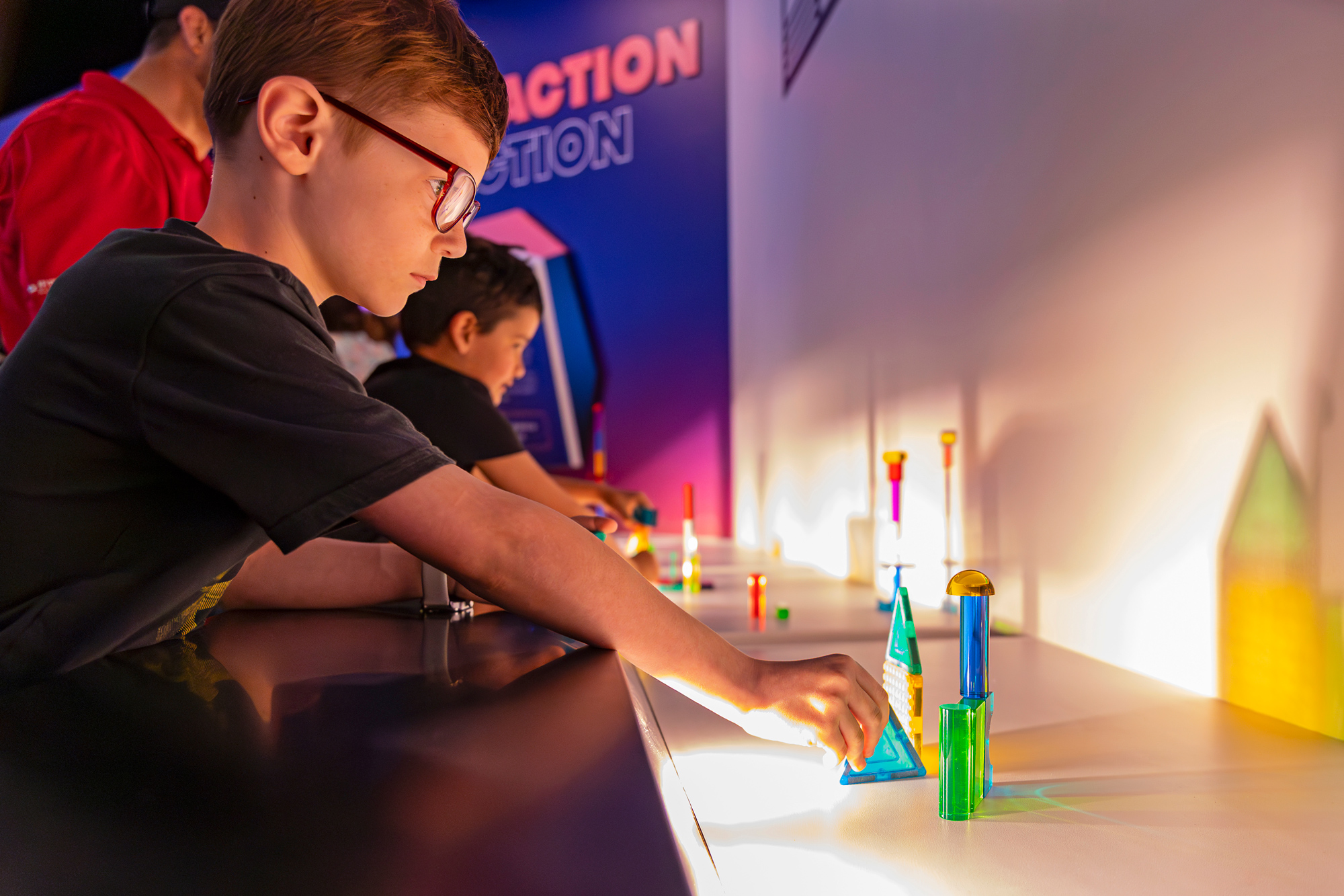 This image shows a student exploring how light bends through objects. He is turning a color piece of plastic to see what happens as light passes through it.